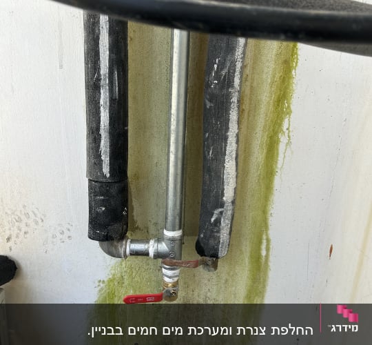 צינורות עם ברז על קיר עם כתמי רטיבות